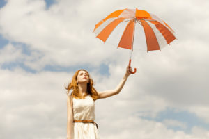 Girl with umbrella at sky background.