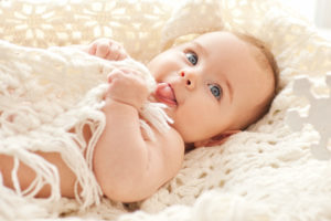 Portrait of small cute girl with blue eyes in her cozy white bed