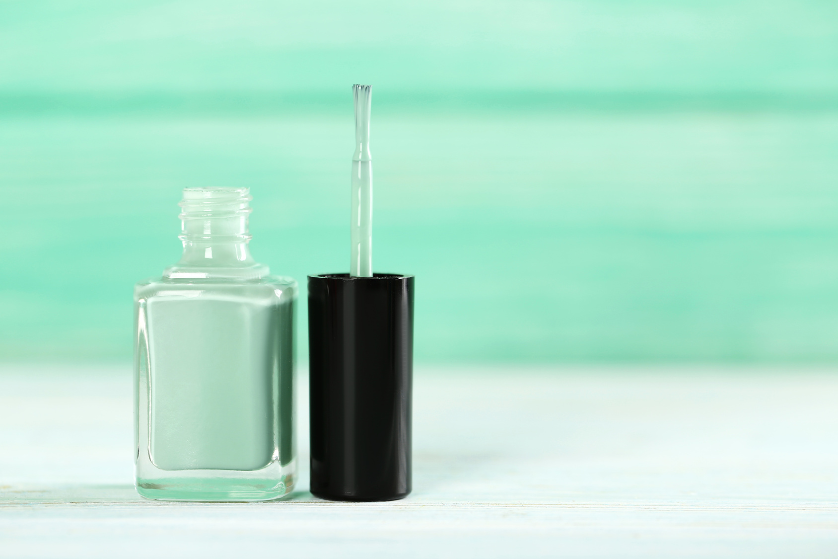 Bottle of nail polish on a wooden table mint green