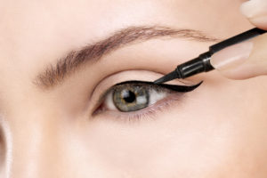 Beautiful model applying eyeliner closeup on eye woman makeup