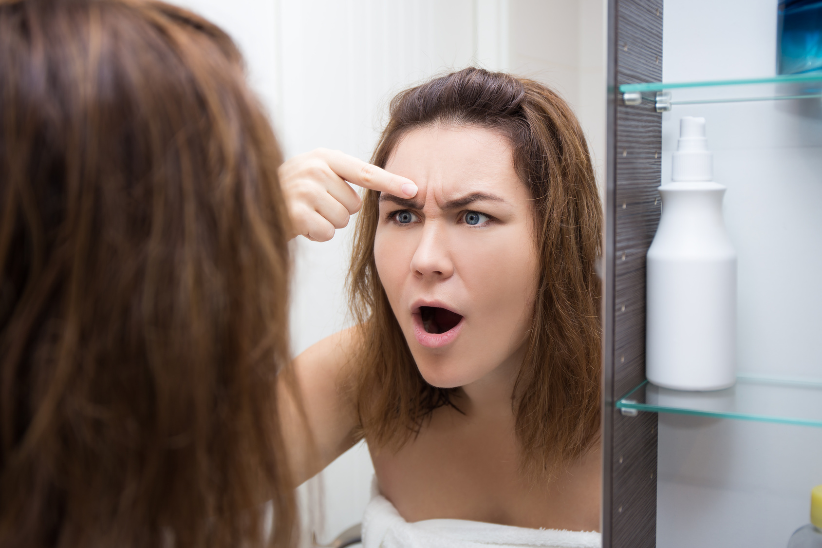 problem skin concept – woman looking at mirror in bathroom