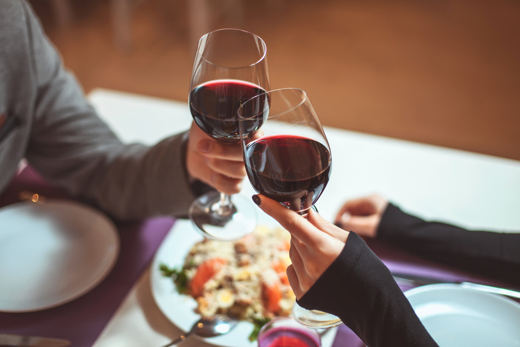 Beautiful young couple with glasses of red wine in luxury restaurant