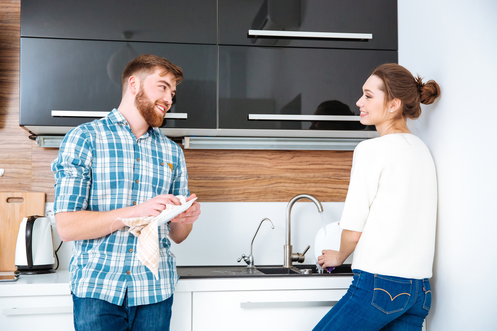 Happy couple washing and wiping diches on kitchen