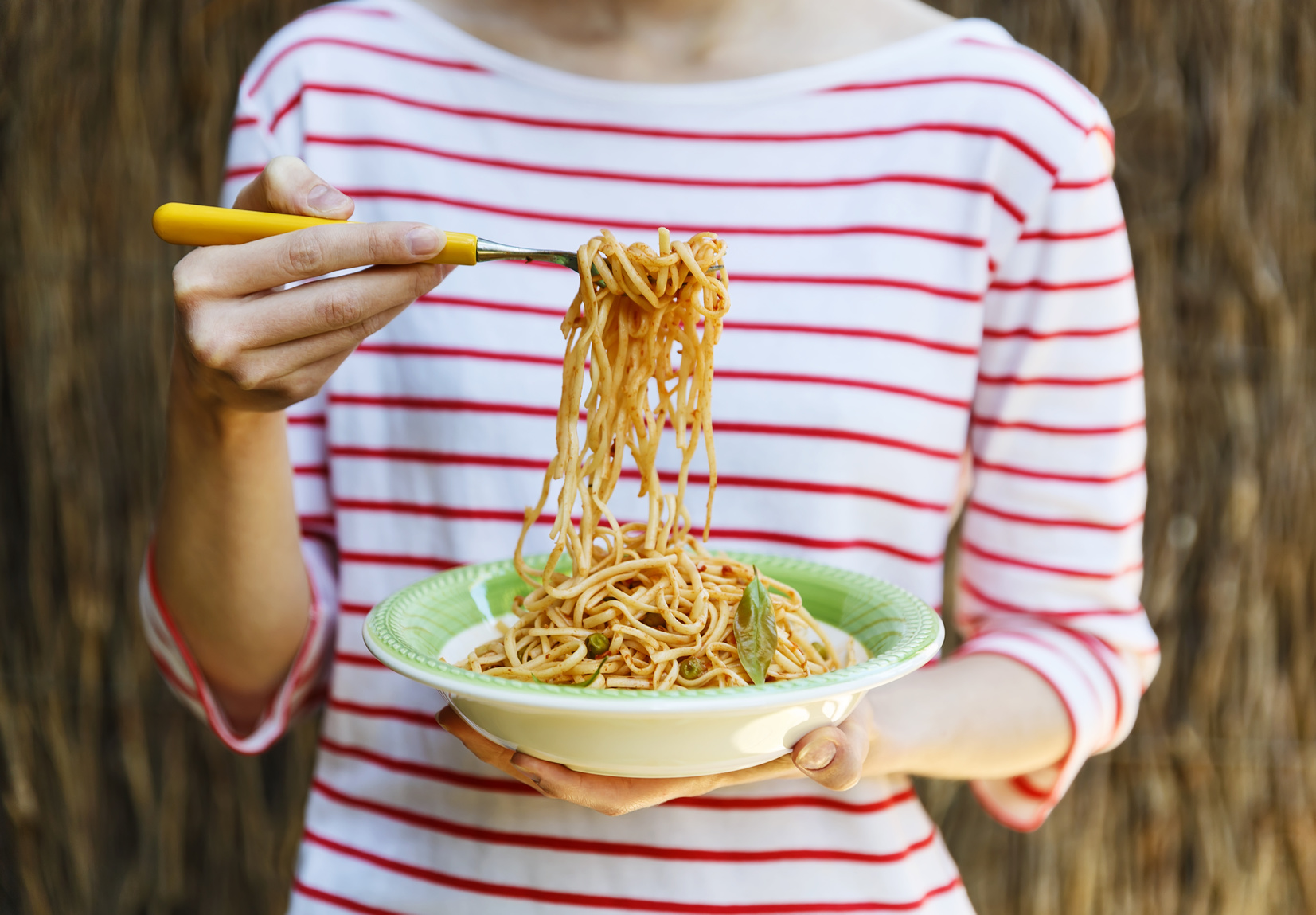 Female hands holding plate with pasta