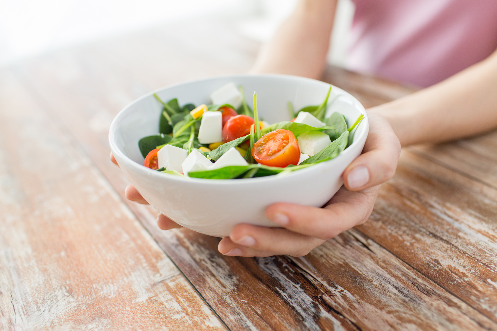 close up of young woman hands showing salad bowl