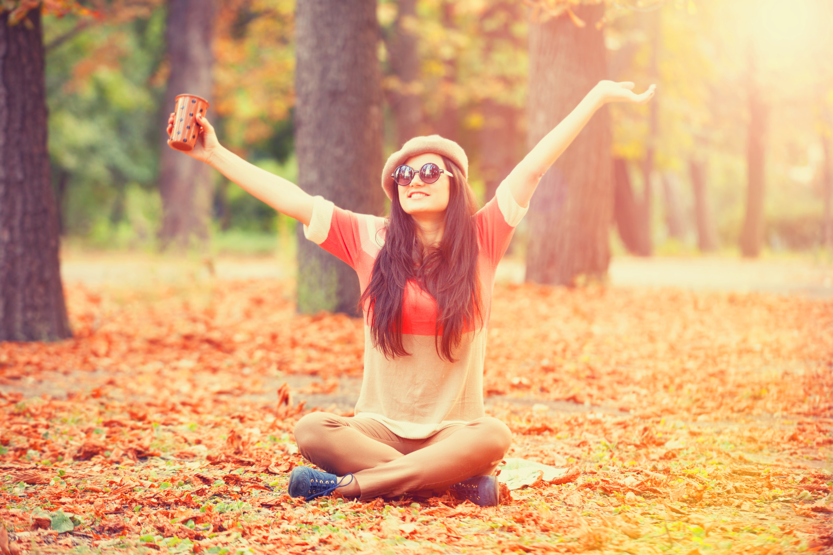 Beautiful brunette girl with cup in the park.