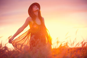 Beautiful woman in golden field at sunset