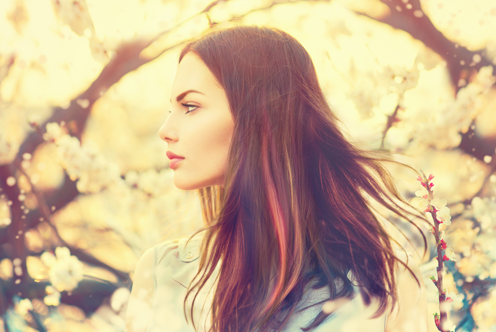 Beautiful model girl with long blowing hair in spring garden
