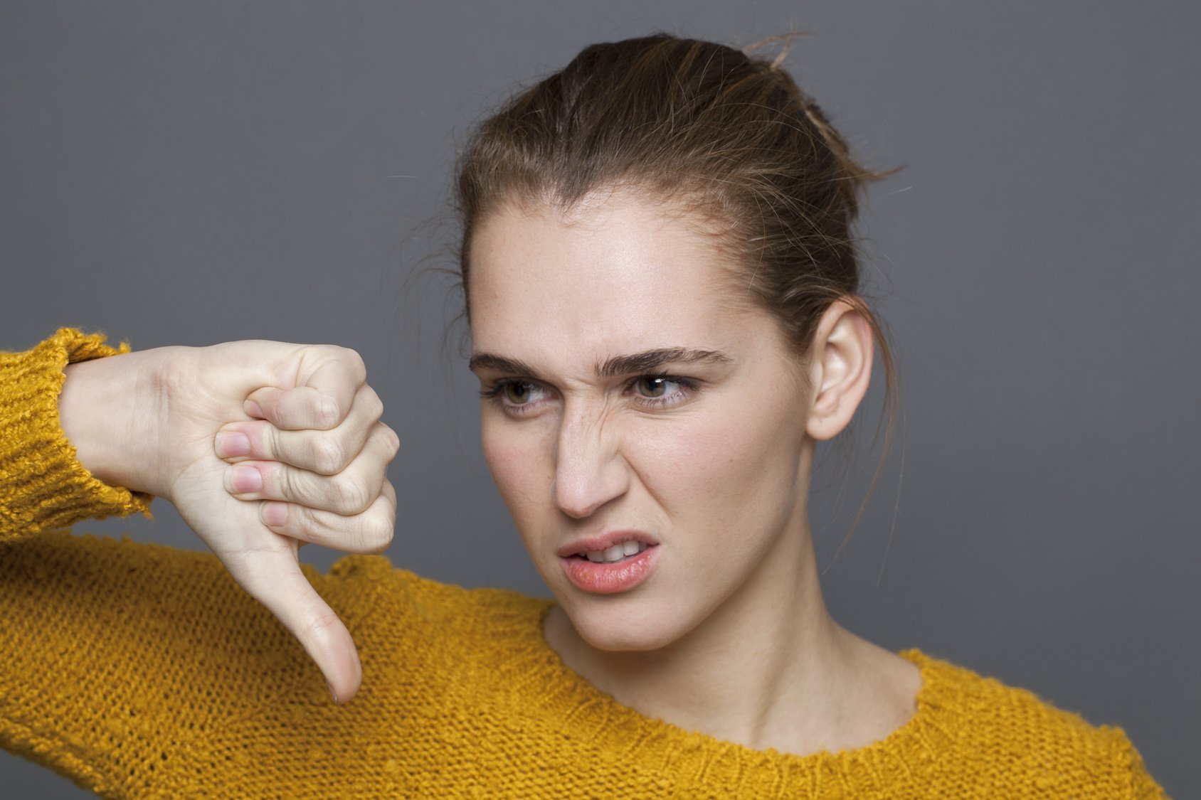 disgusted young woman with thumb down to disapprove expressing frustration