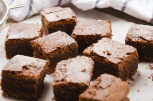chocolate brownie diced baking paper on wooden table with a towel