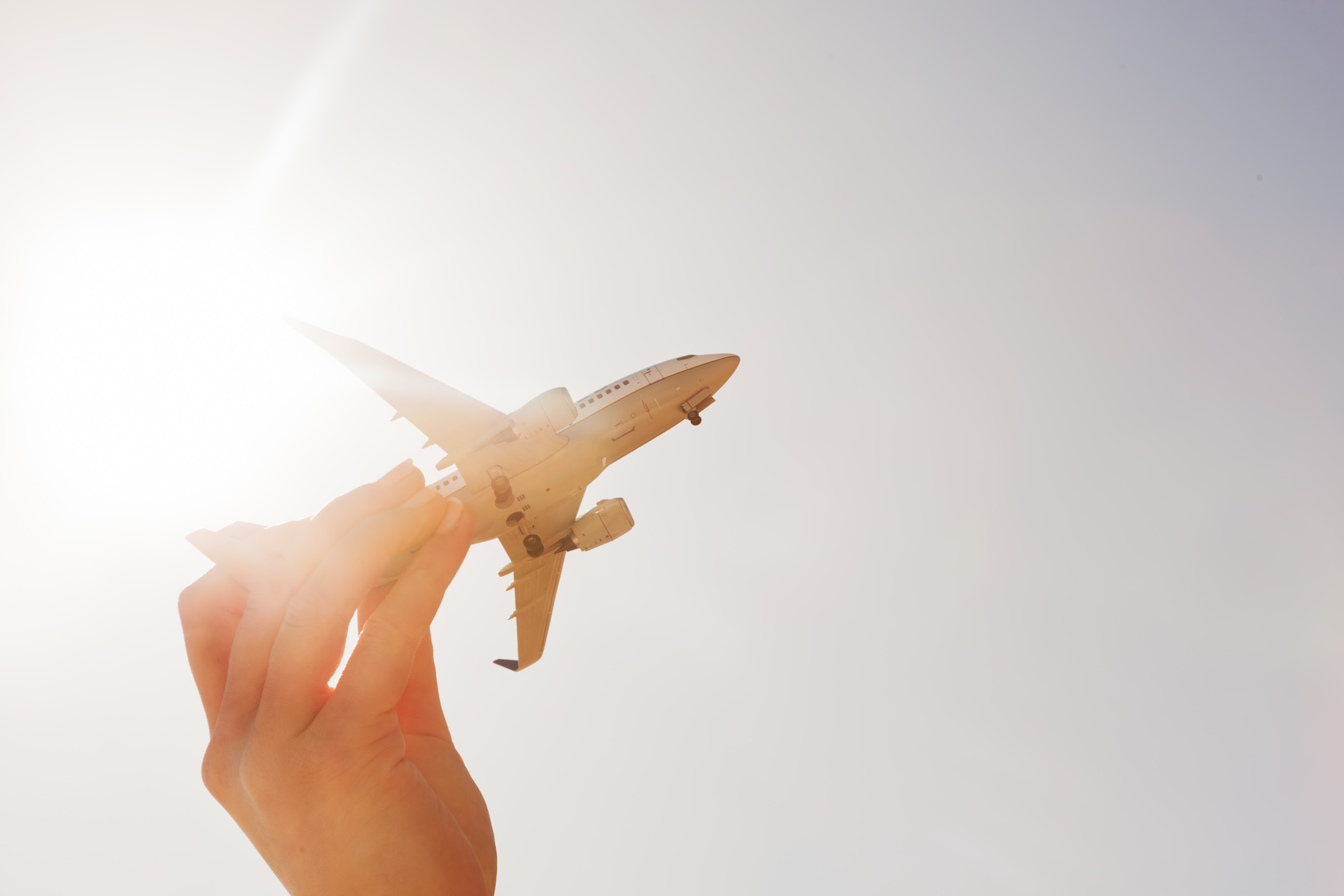 Airplane model in hand on sunny sky. Travel, transportation