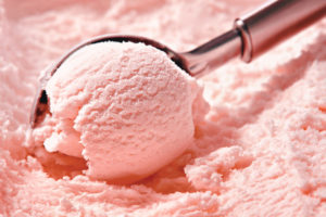 Strawberry ice cream scooped out of container