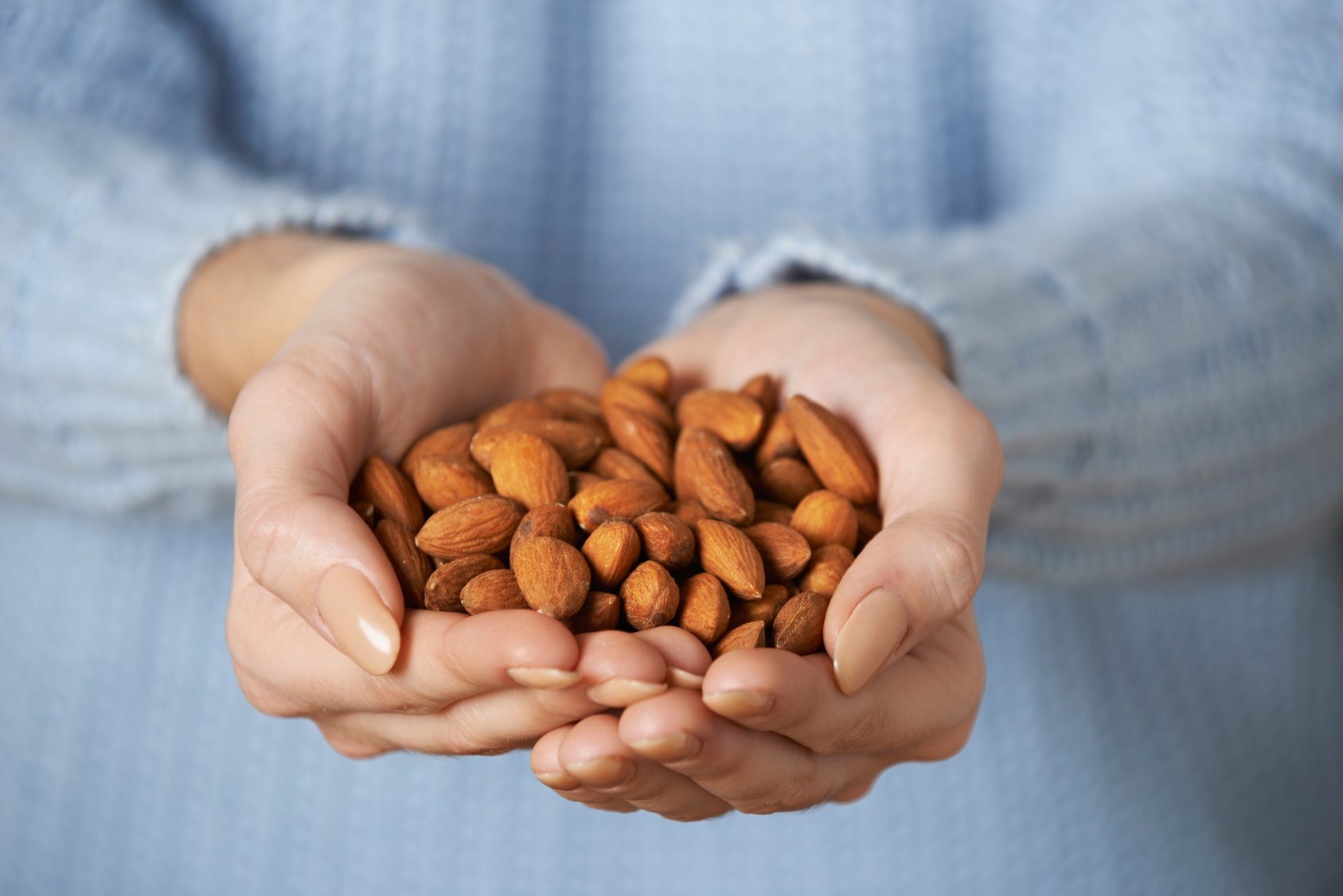 Close Up Of Woman Holding Handful Of Almonds