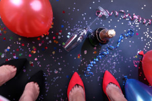 Legs with confetti, champagne and balloons on the floor