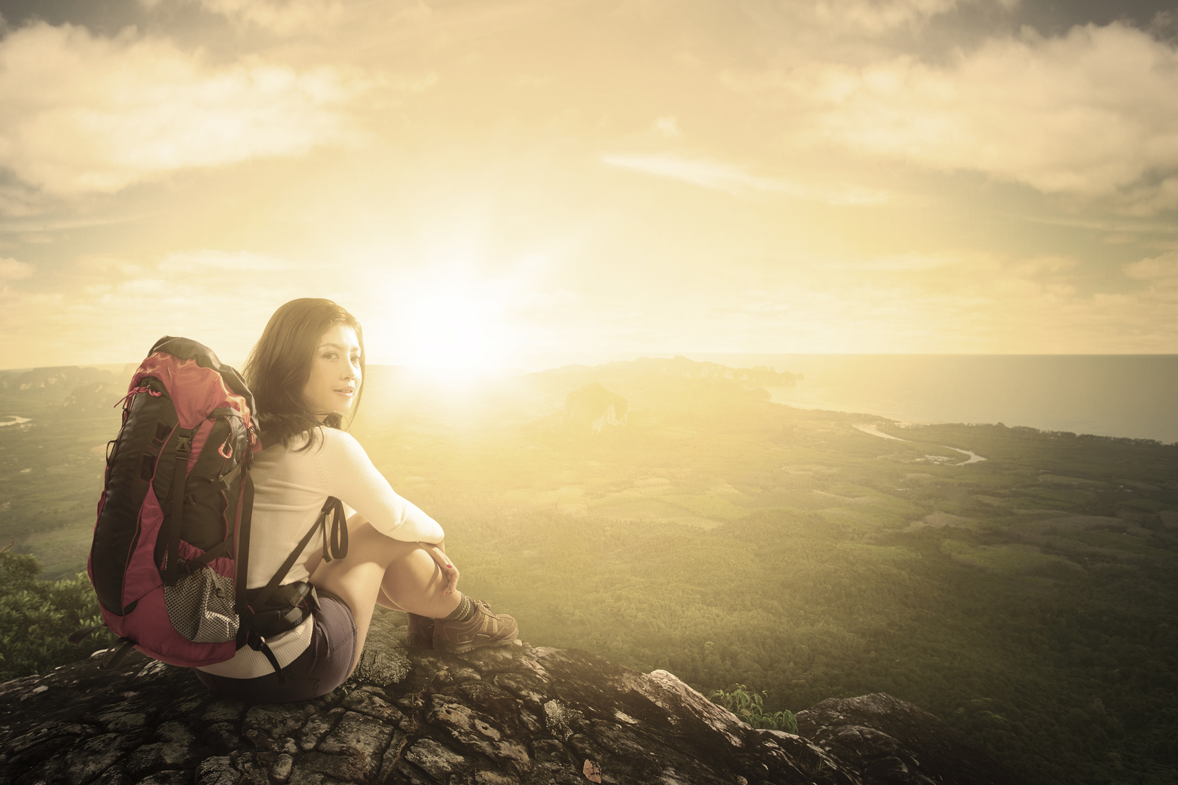 Woman with backpack sitting on mountain