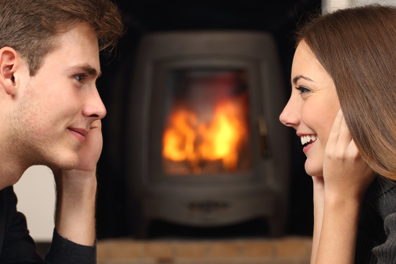 Couple looking each other in front a fireplace