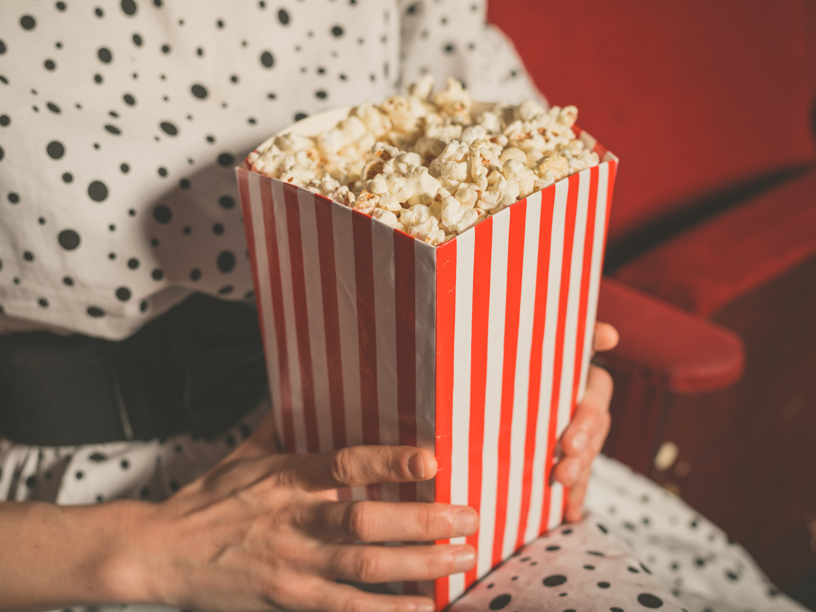 Young woman eating popcorn in movie theater