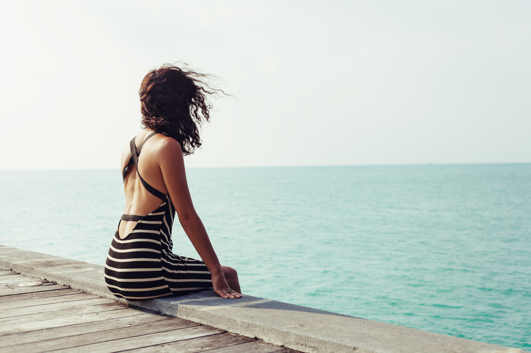 Young pretty woman sitting alone on the pier