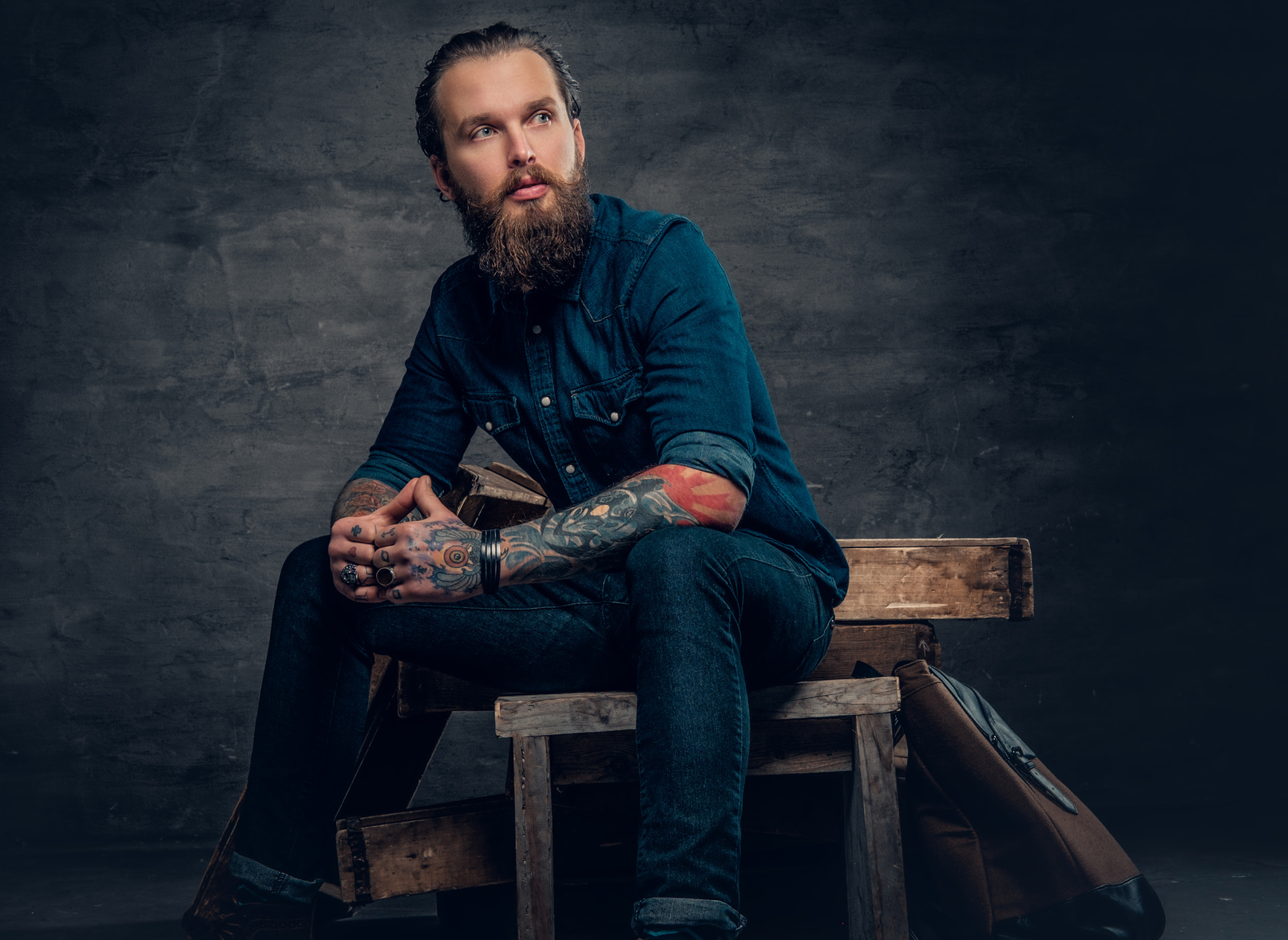 Bearded male with tattoos on arms.