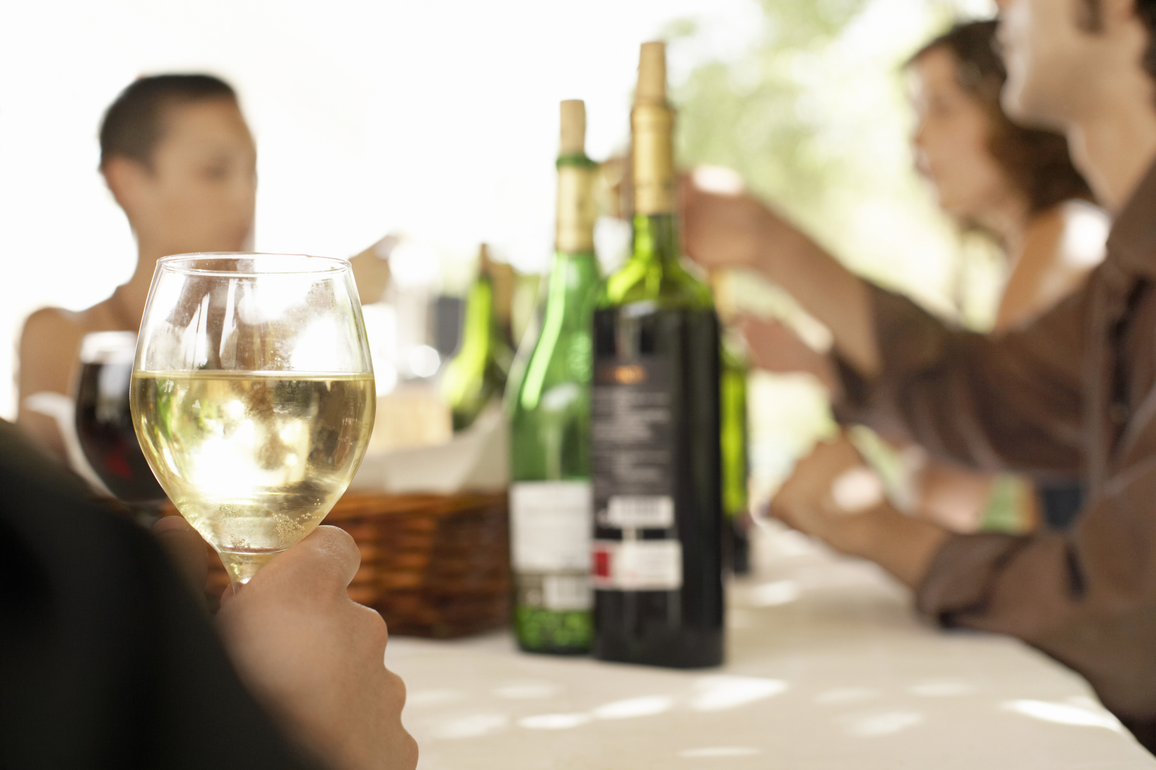 Glass of white wine on table surrounded by people at party