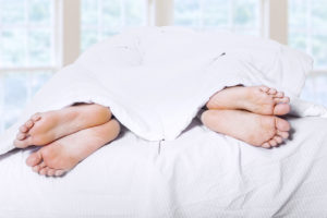 Two pair of feet on bed 1