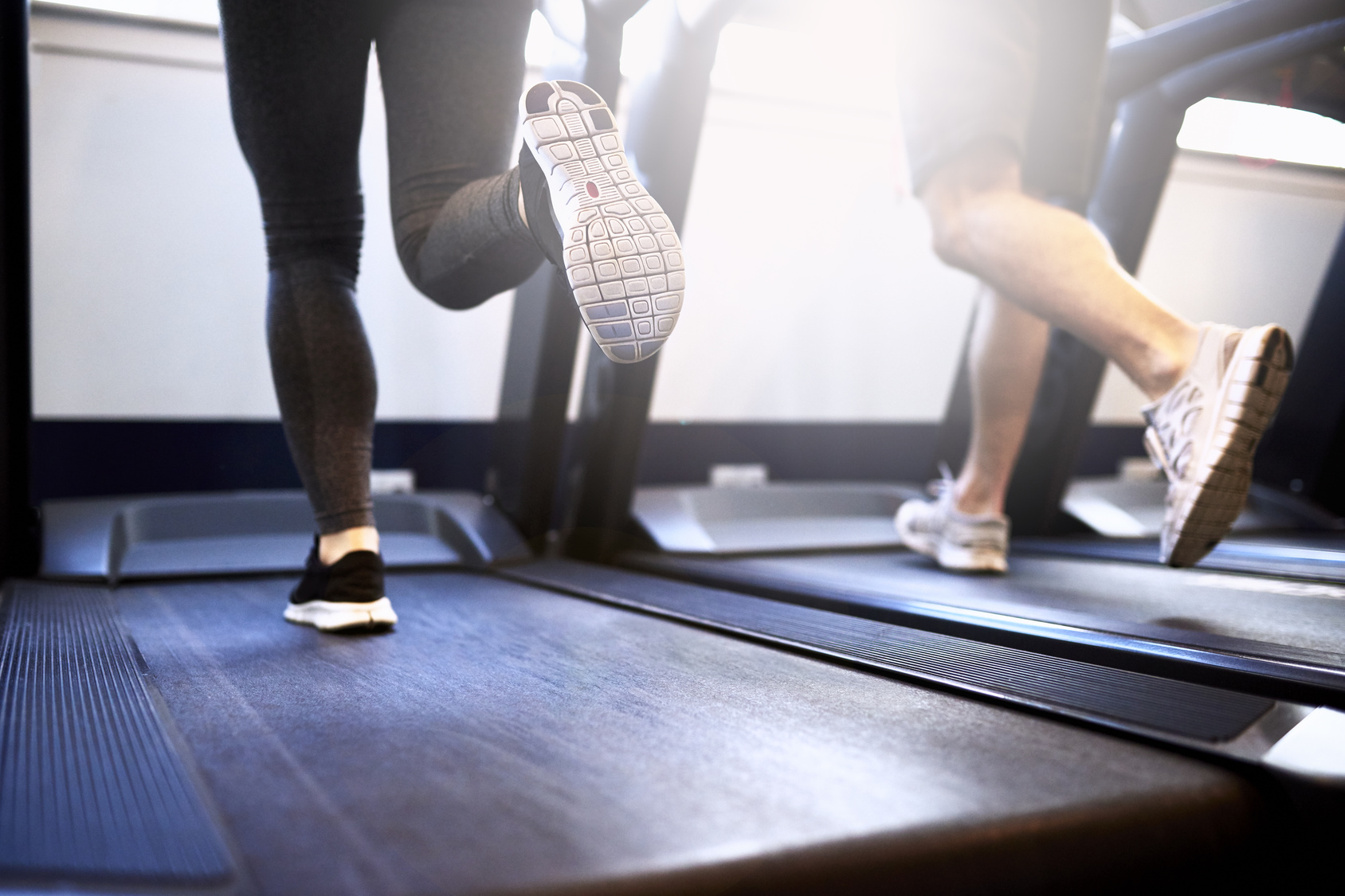 Legs of Fit Couple Exercising on Treadmill Device