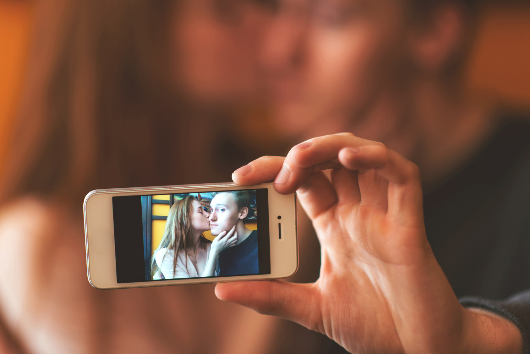 young couple kissing and photographing themselves on the phone