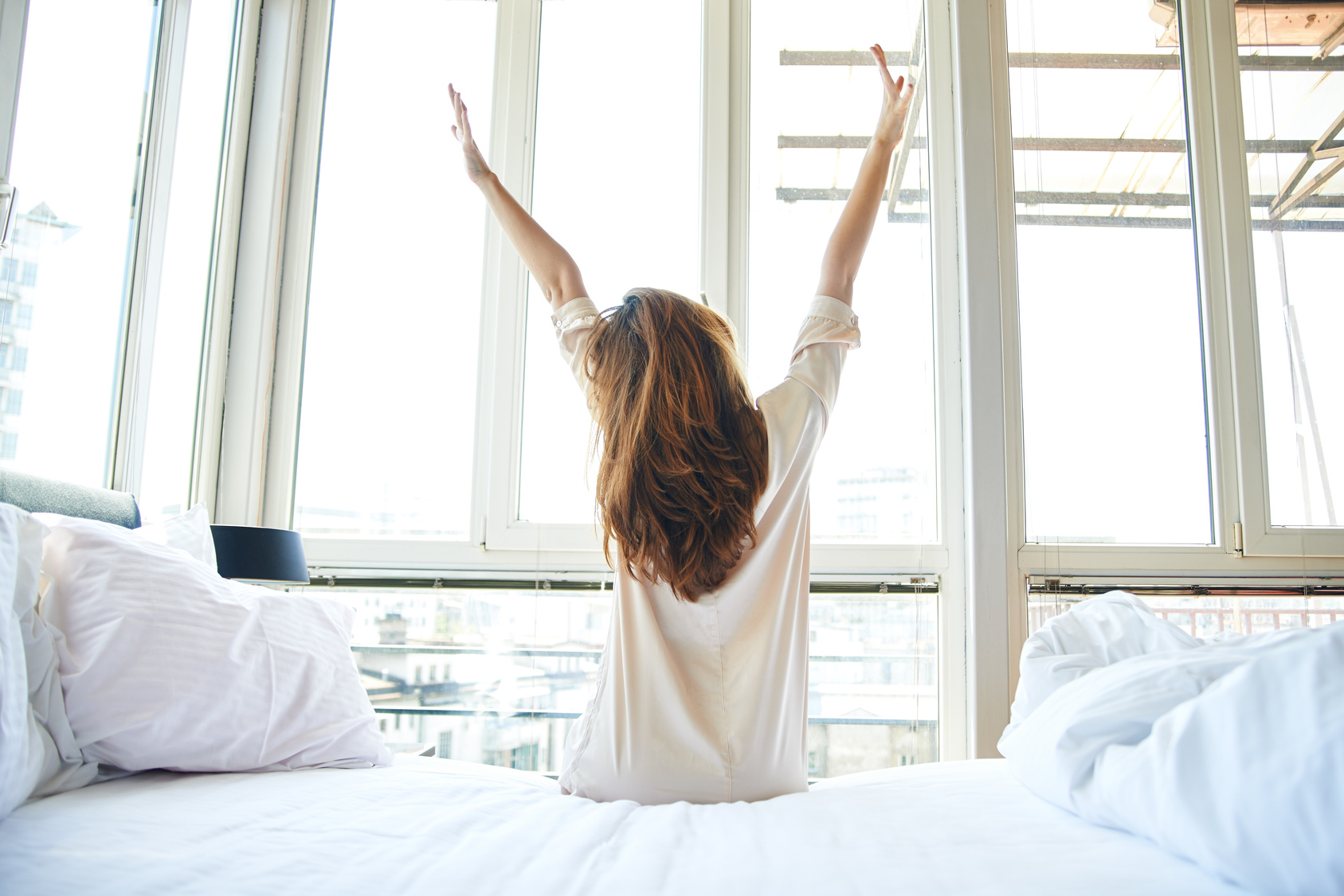 Woman stretching in bed, back view