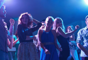 group of happy friends dancing in night club