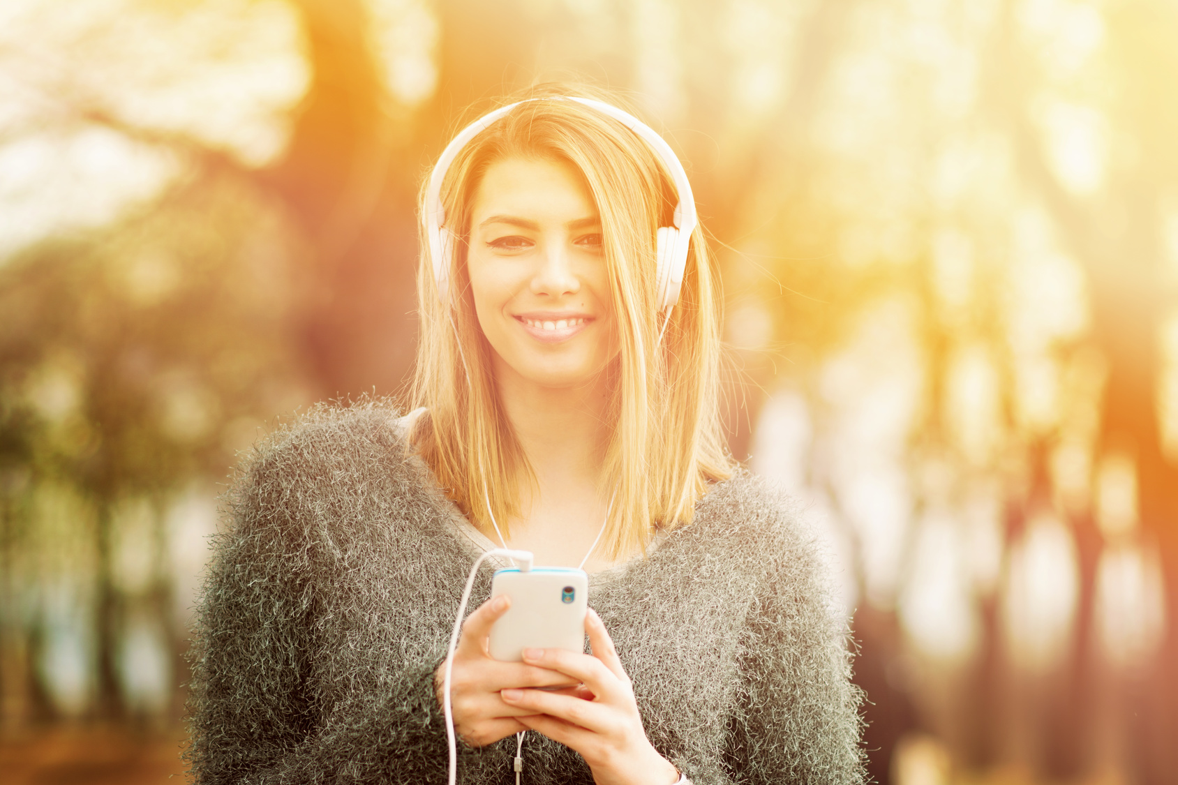 Beautiful young woman listening to music in spring