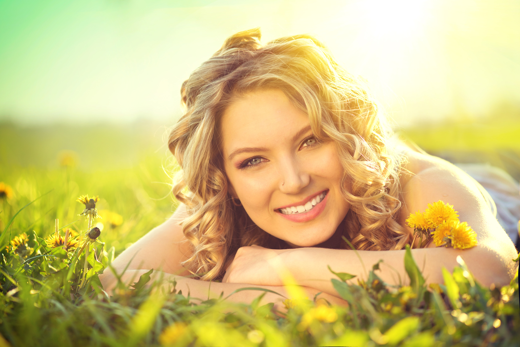 Beautiful young woman lying on a field, enjoying nature