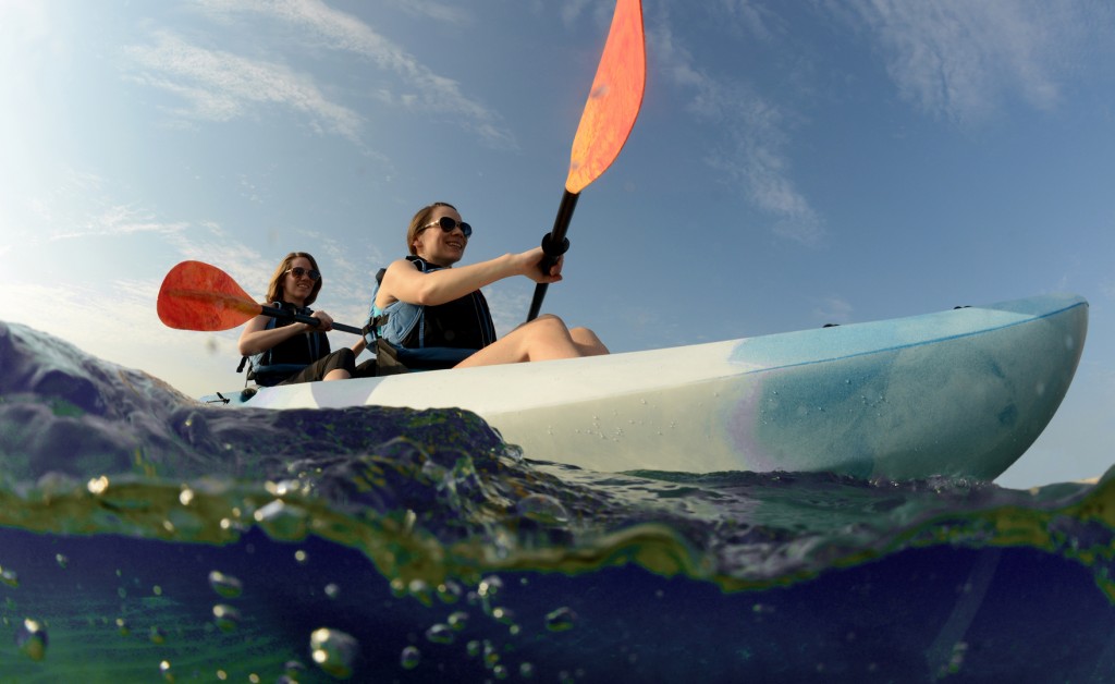 women smiling in blue kayak on tropical ocean