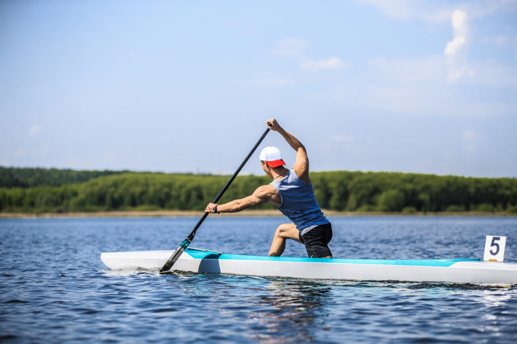 muscular male athlete in a canoe rowing