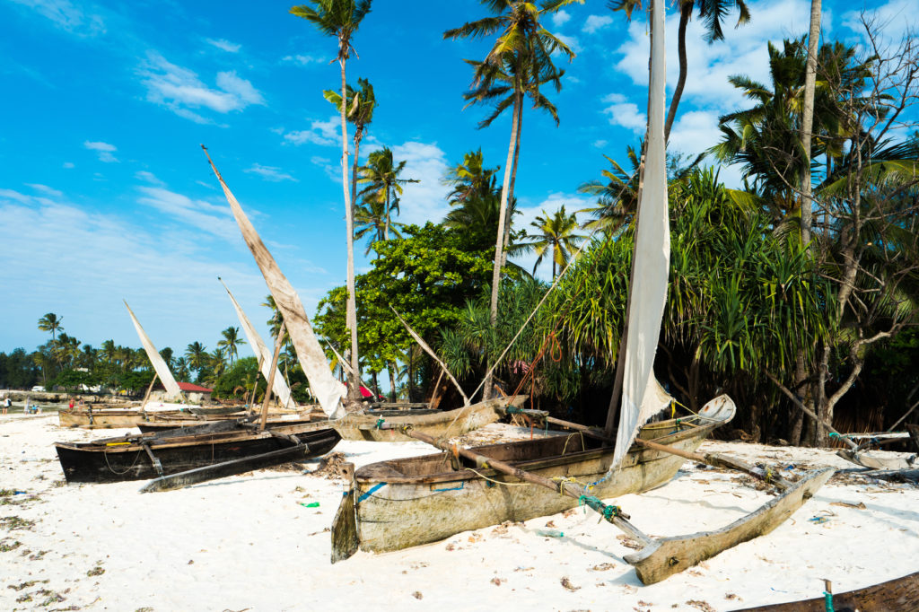 Rustic boats with masts on sandy beach