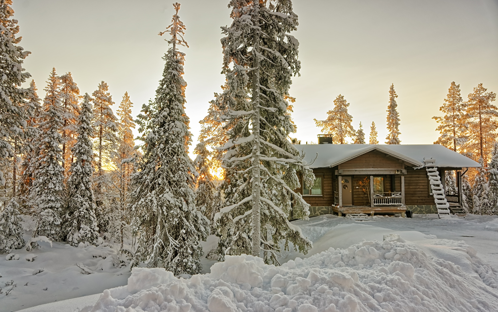 Cottage in snowy winter forest at sunset