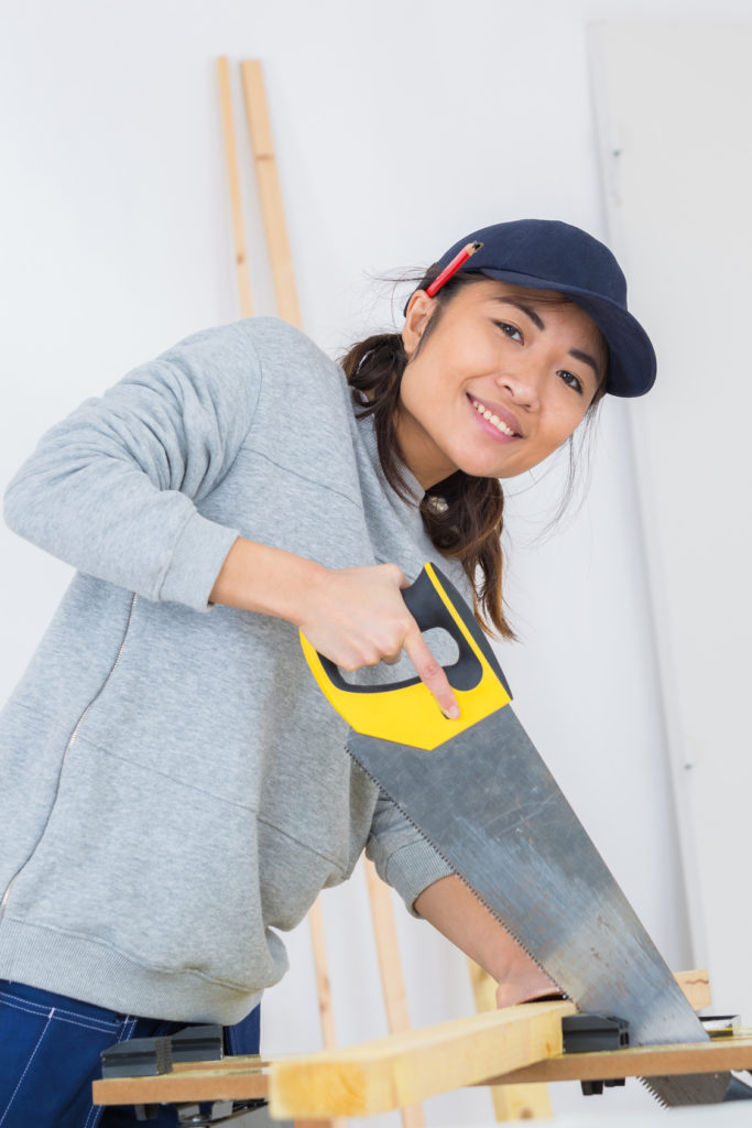 girl is sawing a wooden beam the hand saw