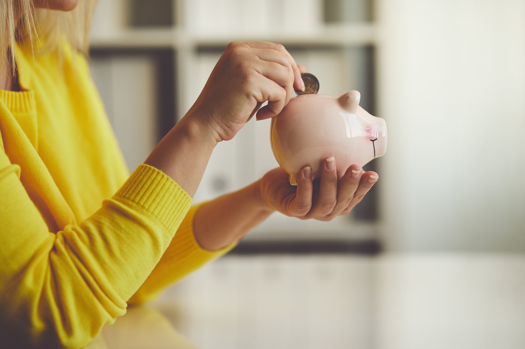 Woman inserts a coin into a piggy bank