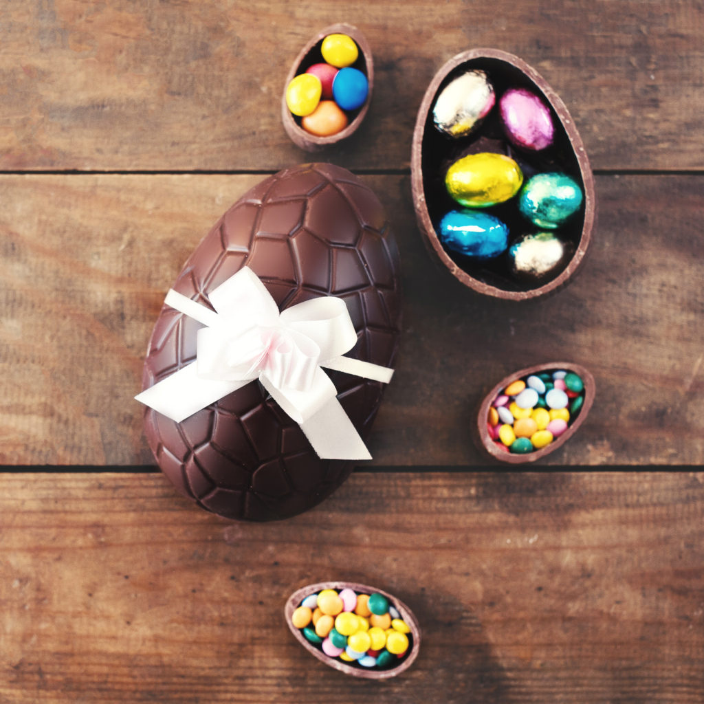 Chocolate Easter eggs on wooden background with ribbon bow and candies. Happy Easter!