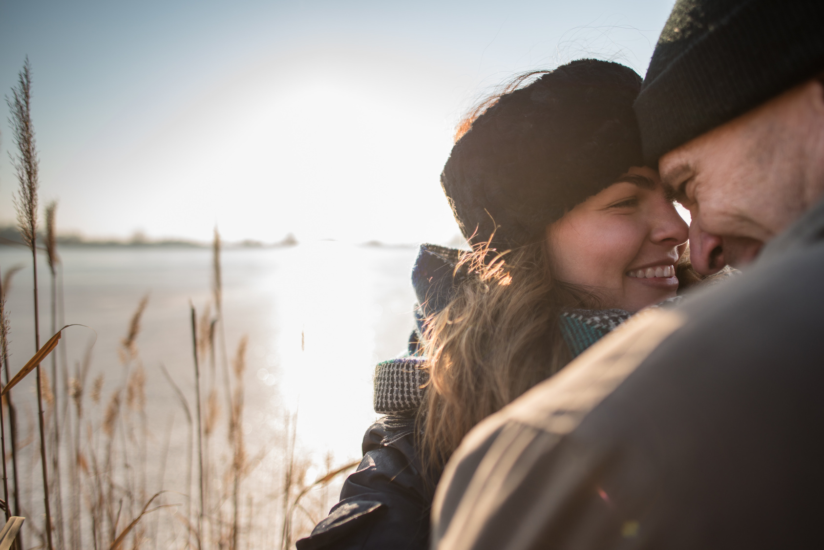 Happy couple embracing, sun in background.