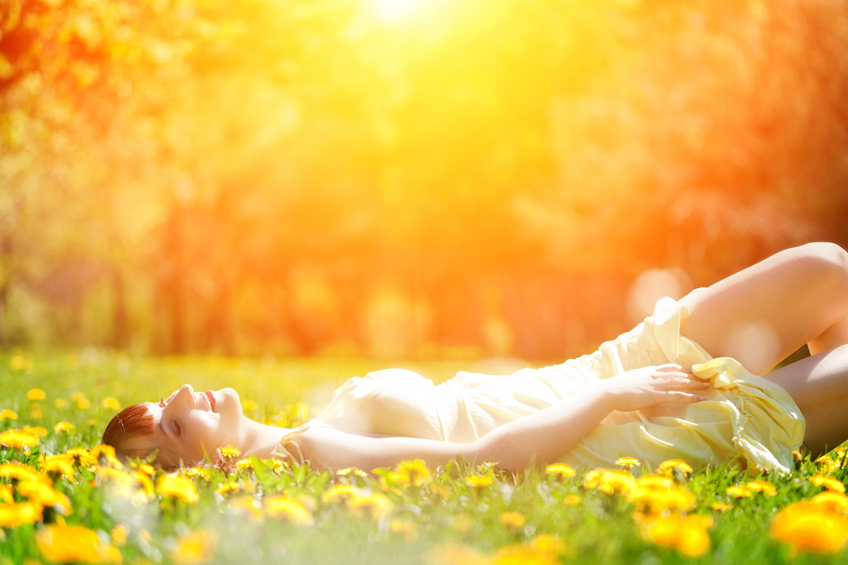 Young beautiful woman lying on grass in spring flowers, relax