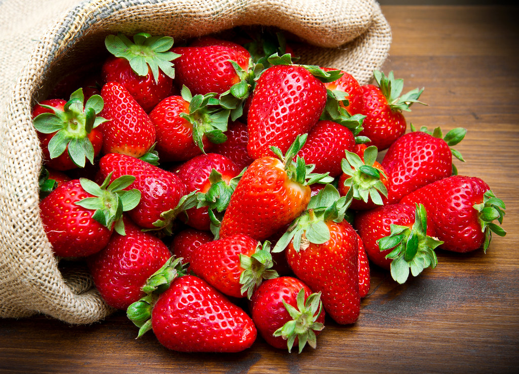 fresh strawberry in burlap sack on wood