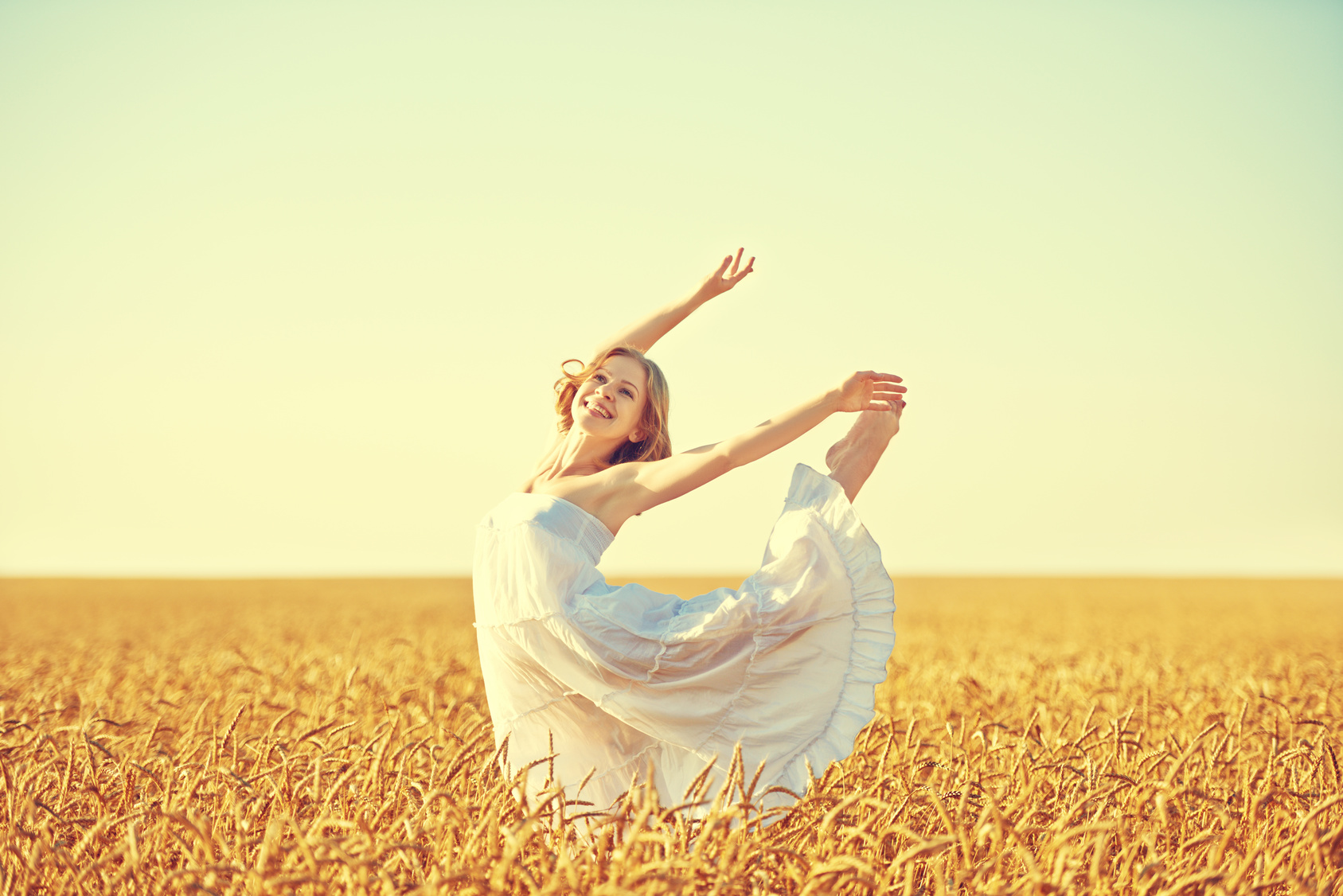 happy young woman enjoying life in golden wheat field