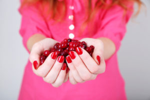 Woman hands holding ripe red cranberries, close up.