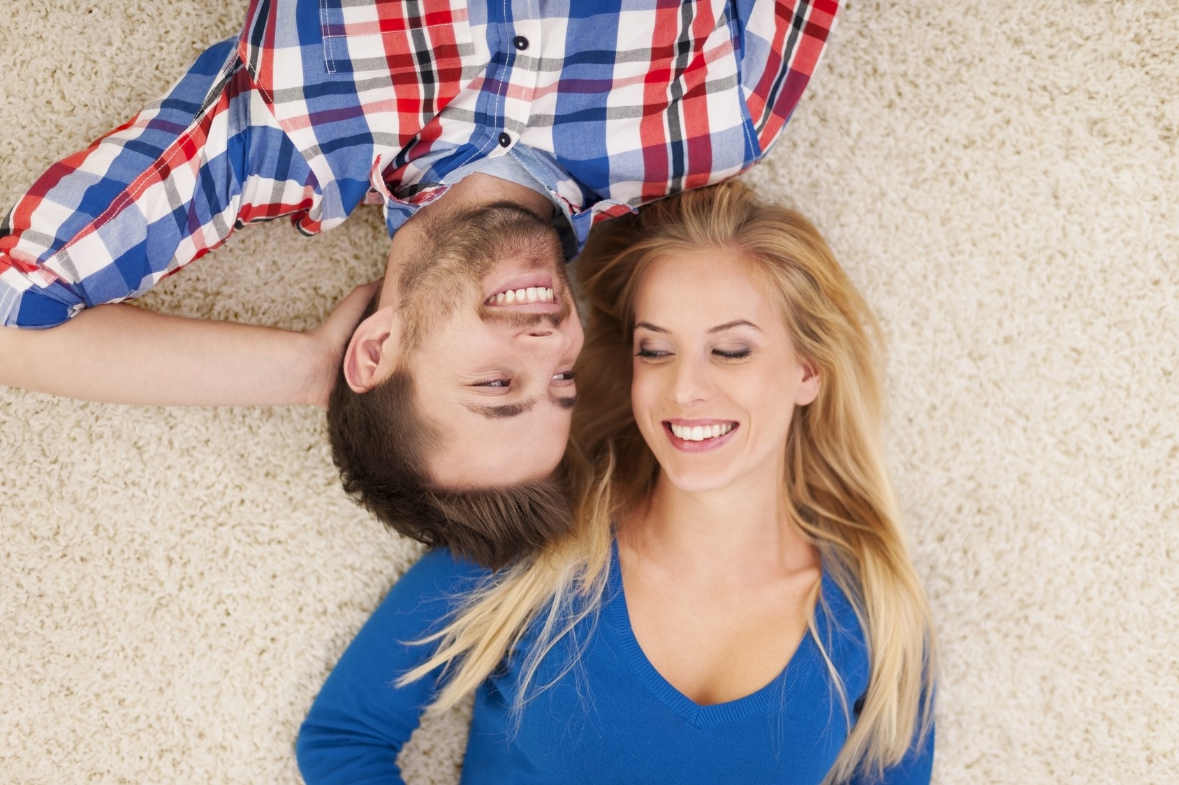 Cute young couple lying on carpet and look at each other