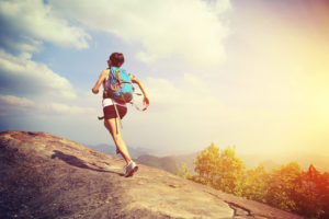 woman hiker running at on mountain peak rock