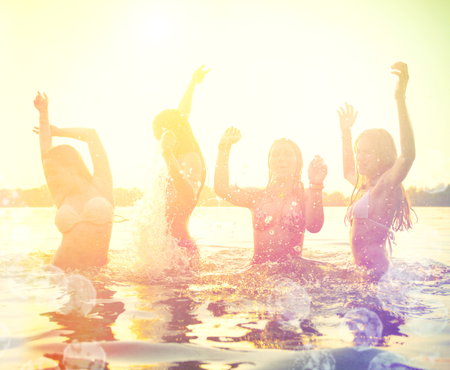 Group of happy teen girls playing at the beach on sunset