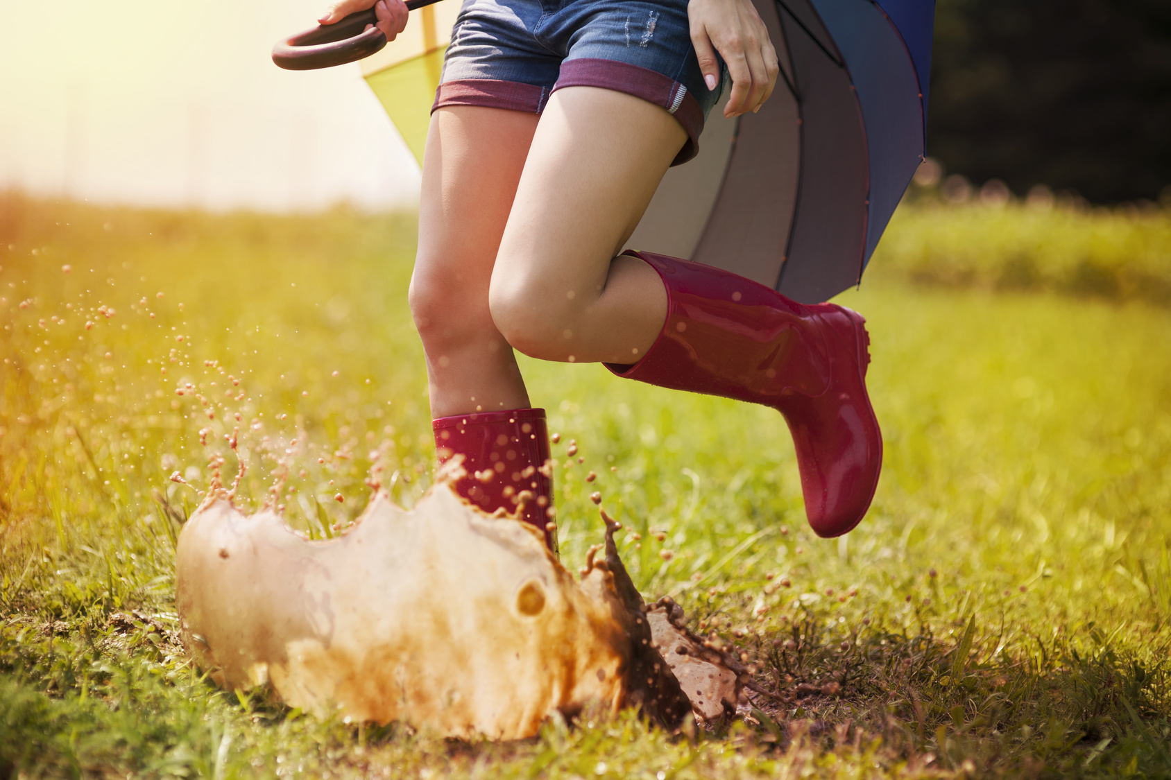 Jumping woman with umbrella and rubber boots