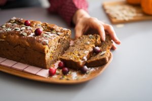 Young housewife taking piece of freshly baked pumpkin bread