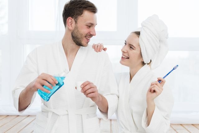 front-view-couple-bathrobes-with-mouthwash-toothbrush