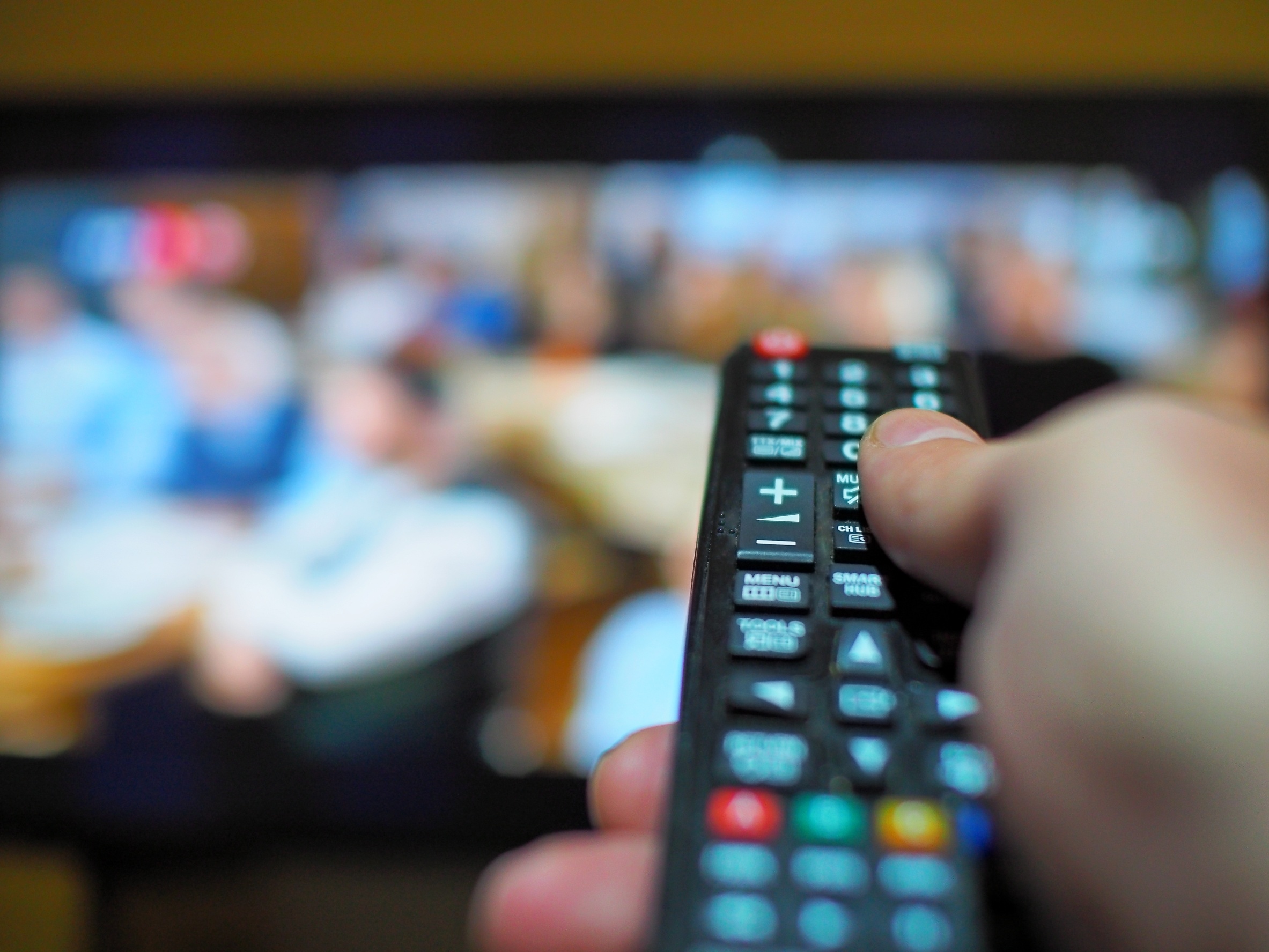 adult male hand while holding television remote control .
